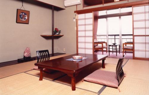 a living room with a wooden table and chairs at Hotel Shiiya in Sado