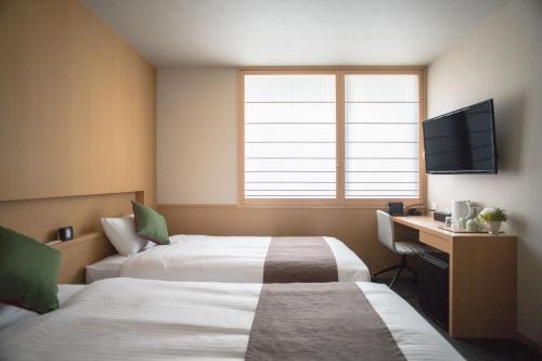 a room with two beds and a desk and a television at Number 6 Nijo in Kyoto