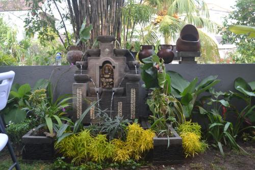 a garden with a fountain with plants and vases at Master Homestay in Amed
