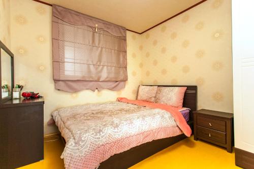 a bedroom with a bed and a dresser and a window at Nuyoungnayoung Pension in Seogwipo