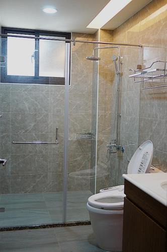 a bathroom with a glass shower with a toilet at Yo Muma Homestay in T'ien-wei