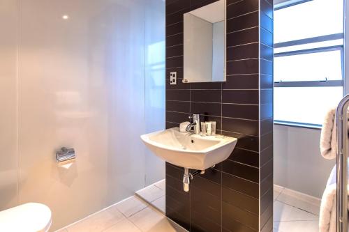 La salle de bains est pourvue d'un lavabo et d'un miroir. dans l'établissement Quest Newmarket Serviced Apartments, à Auckland