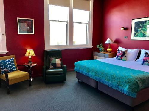 a bedroom with red walls and a bed and a chair at Vine Valley Inn in Cessnock