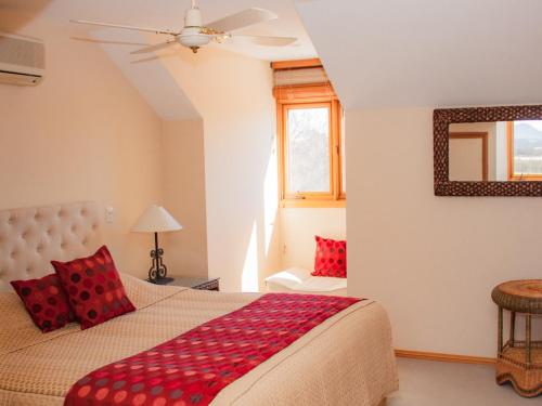 a bedroom with a bed with red pillows at Berenbell Vineyard Retreat in Pokolbin