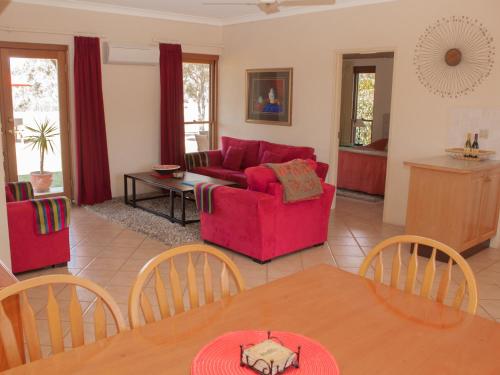 a living room with a red couch and a table at Berenbell Vineyard Retreat in Pokolbin