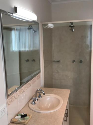 a bathroom with a sink and a shower with a mirror at Beachcomber Motel & Apartments in Apollo Bay