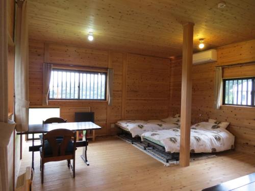 Cabaña de madera con 2 camas y mesa. en Cottage Orange House Yakushima en Yakushima