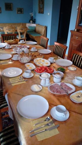 a long table with white plates and food on it at Gospodarstwo Agroturystyczne-Pensjonat SAD in Podgórzyn