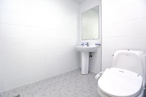 ein weißes Bad mit einem WC und einem Waschbecken in der Unterkunft Marine Port Resort in Seogwipo