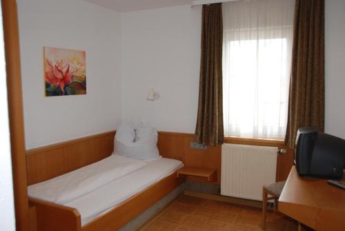 Habitación pequeña con cama y TV. en Hotel-Restaurant Zum Goldenen Hahnen, en Markgröningen