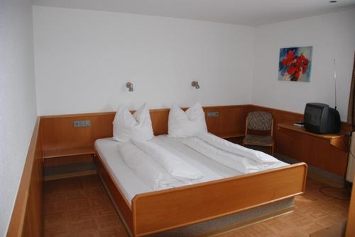 Schlafzimmer mit einem Bett mit weißer Bettwäsche und einem TV in der Unterkunft Hotel-Restaurant Zum Goldenen Hahnen in Markgröningen