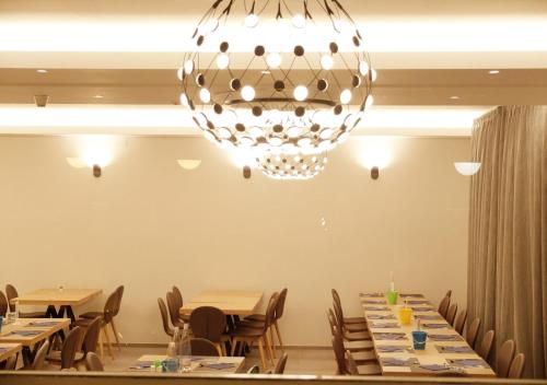 a dining room with tables and a chandelier at Hotel Aurea in Rimini