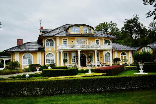 a large yellow house with a garden in front of it at Dworek Hetmanski in Stargard