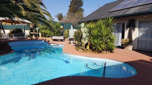 a large swimming pool in front of a house at Sleep Eezy Cottages in Benoni