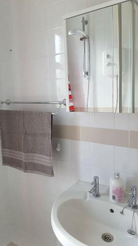 a white bathroom with a sink and a mirror at Dumfries Central apartment in Dumfries