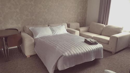 a bedroom with a bed and a couch and a chair at Dumfries Central apartment in Dumfries