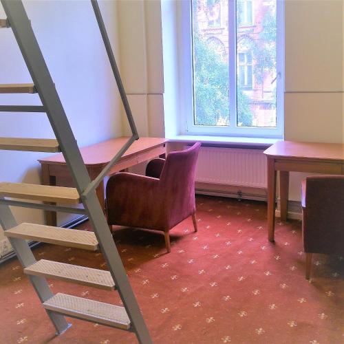 Pokój z drabiną, krzesłem, biurkiem i stołem w obiekcie Hostel Kwadrans w mieście Gliwice