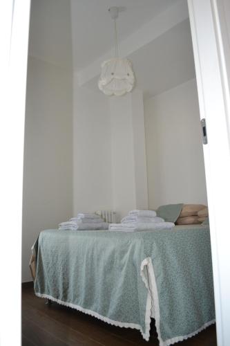 a white room with a bed with a green blanket at Casa Porta Vecchia in Monopoli