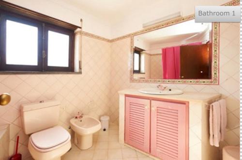 Un baño con inodoro, lavabo y espejo. en By the sea in the center @ Ericeira, en Ericeira