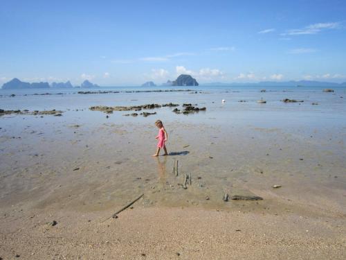 a little girl standing in the water on the beach at Melina Beach Front Bungalows in Tha Lane Bay