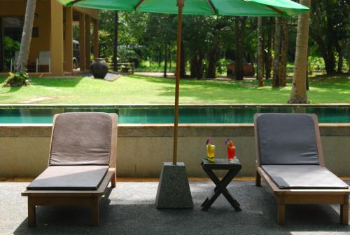 two chairs and an umbrella next to a table with drinks at Melina Beach Front Bungalows in Tha Lane Bay