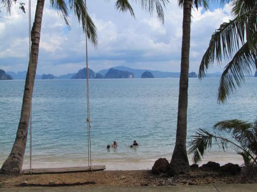 two people on a swing in the water between two palm trees at Melina Beach Front Bungalows in Tha Lane Bay
