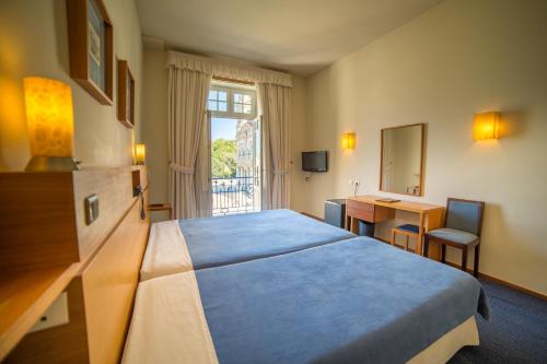 a hotel room with a large bed and a desk at Hotel do Templo in Braga