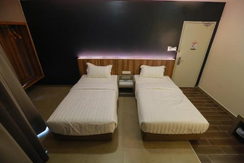 two twin beds in a small room with a door at Pantai Regal Hotel in Kuantan