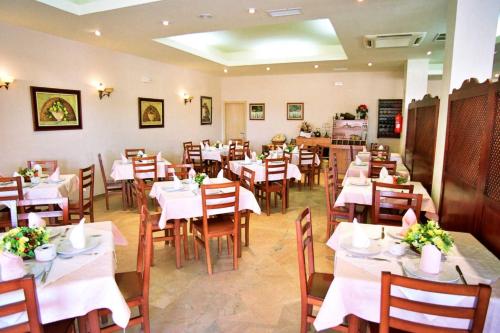 uma sala de jantar com mesas e cadeiras brancas em Hostal Restaurante Hermanos Zamora em Palma del Río