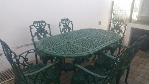 a table with four chairs and a green table and chairs at Uitenhage Apartment - 4 Graaff-Reinet Rd in Uitenhage