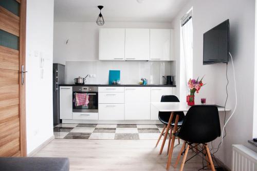 uma cozinha com armários brancos e uma mesa e cadeiras em Kapart City em Rzeszów