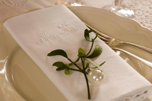 a white napkin with a green plant on a plate at Le Moulin Bregeon in Linières-Bouton