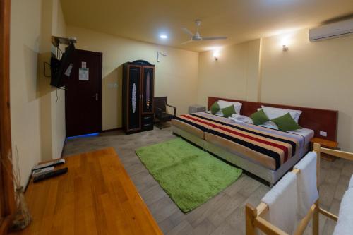 a bedroom with a bed and a green rug at Annama Lodge and Dive in Hoarafushi