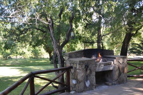 a stone fire pit in a park next to a fence at Moholoholo Ya Mati in Kampersrus AH
