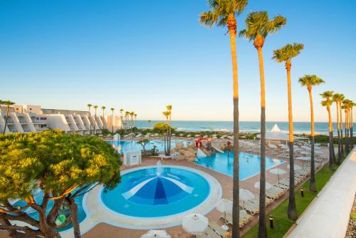 a view of the pool at a resort with palm trees at Iberostar Waves Royal Andalus in Chiclana de la Frontera