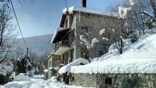 a building covered in snow next to a mountain at Lydia Lithos Mountain Resort in Metamorfosi