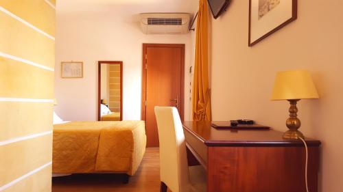 a bedroom with a bed and a desk with a lamp at Hotel Aurora in Verona
