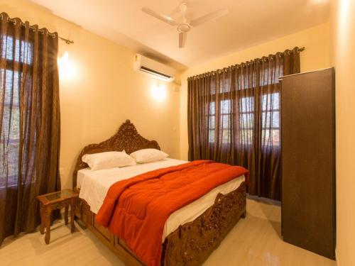 a bedroom with a bed with an orange blanket at Saudades Homestays in Majorda
