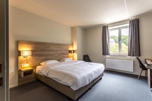 a bedroom with a large bed and a window at Ambassador Hotel Eupen in Eupen
