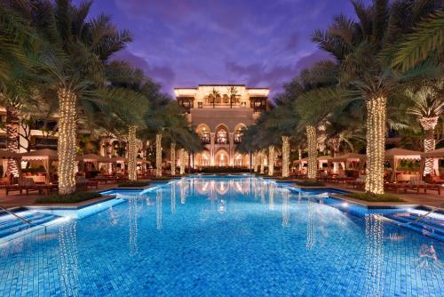 une grande piscine avec des palmiers en face d'un bâtiment dans l'établissement Palace Downtown, à Dubaï