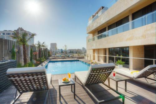 a pool with chairs and tables in front of a building at The House Boutique Suites in Amman