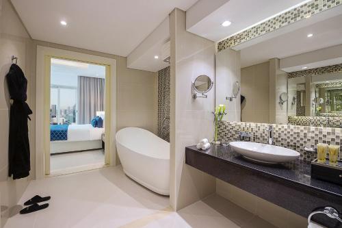 a hotel room with a tub, toilet, and sink at DAMAC Maison Distinction in Dubai
