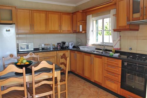 a kitchen with wooden cabinets and a table with a bowl of fruit at OurMadeira - Casa Vista Bela in Estreito da Calheta
