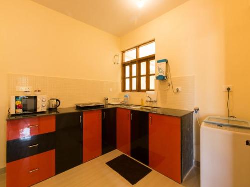 a kitchen with a black and red counter top at Saudades Homestays in Majorda