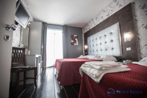 a bedroom with two beds with red sheets and a window at Hotel Relax Roma Nord in Fiano Romano
