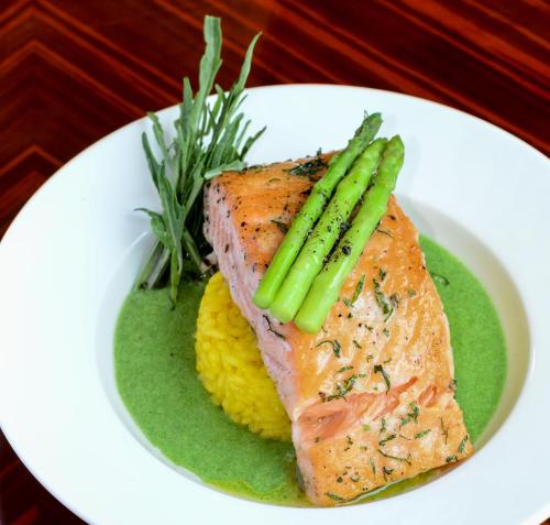 a white plate with a piece of salmon and asparagus at Howard Johnson by Wyndham, Kolkata Airport in Kolkata