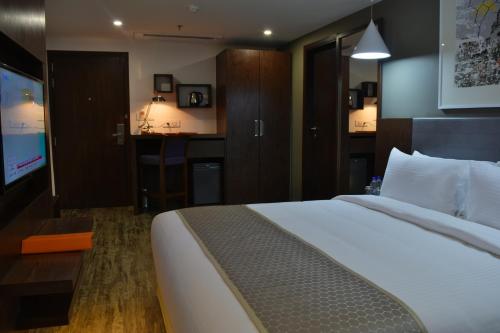 a hotel room with a large bed and a television at Howard Johnson by Wyndham, Kolkata Airport in Kolkata