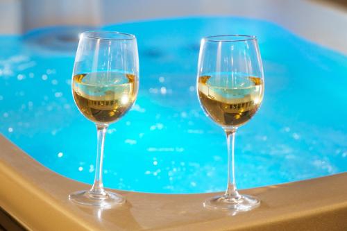 two glasses of wine sitting next to a swimming pool at Aenos Hotel in Argostoli