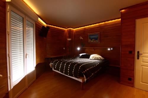 une chambre avec un lit dans une pièce aux murs en bois dans l'établissement Chalet de TARA - Grand appartement esprit chalet - piscine chauffée - Genève, à Collonges-sous-Salève
