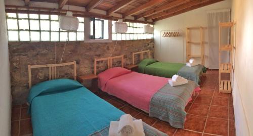 drie bedden in een kamer met een stenen muur bij Casas da Lagoa in Santo Isidoro